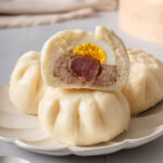 A sliced open banh bao on a pile of banh baos.