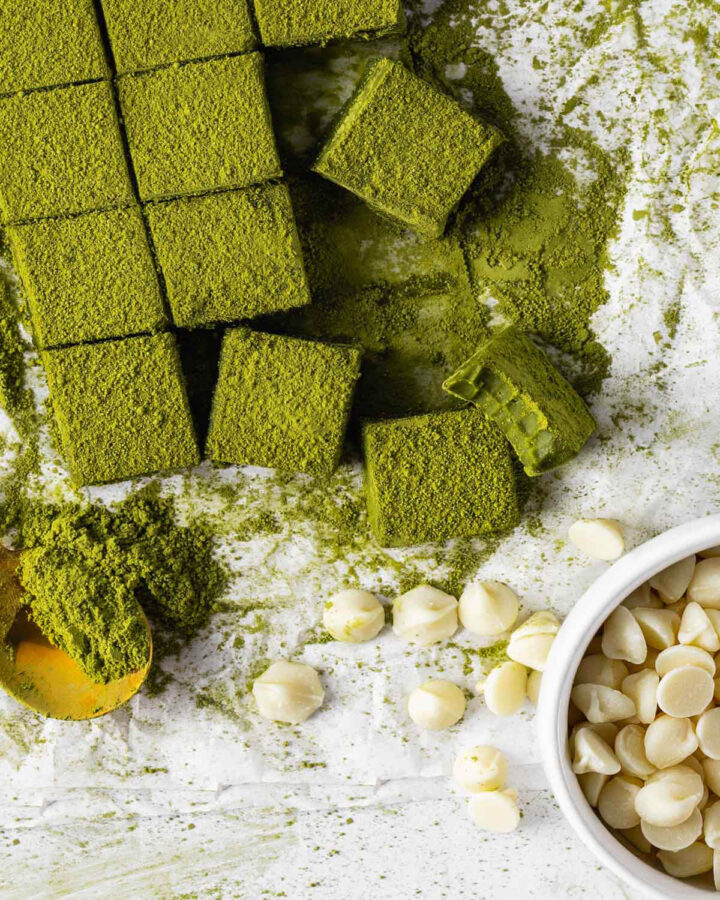 Overhead shot of chocolates staged with a spoon of matcha and bowl of white chocolate chips.