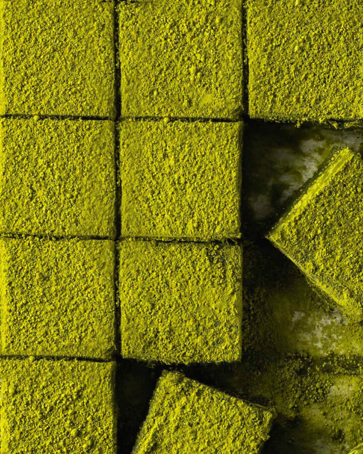 Overhead shot of a grid of matcha squares with a few scattered in the bottom right corner.