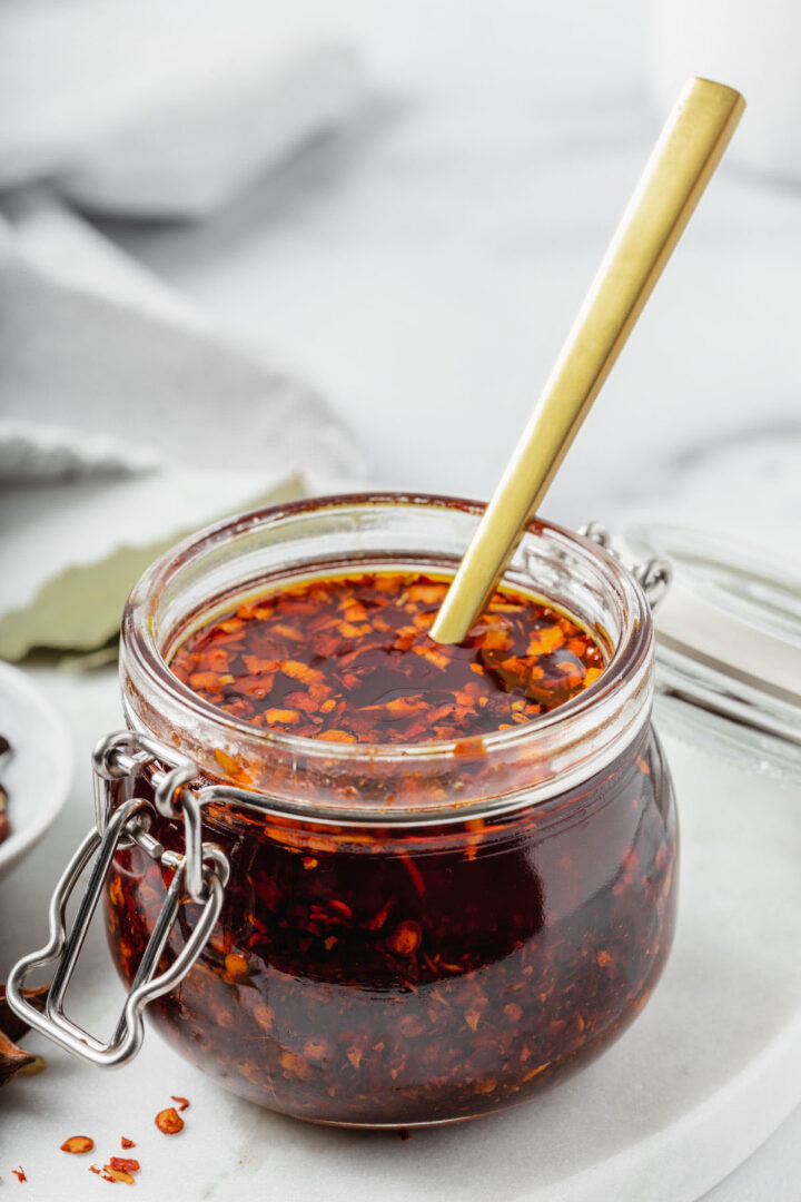 A jar of chinese chili oil with a spoon inside.