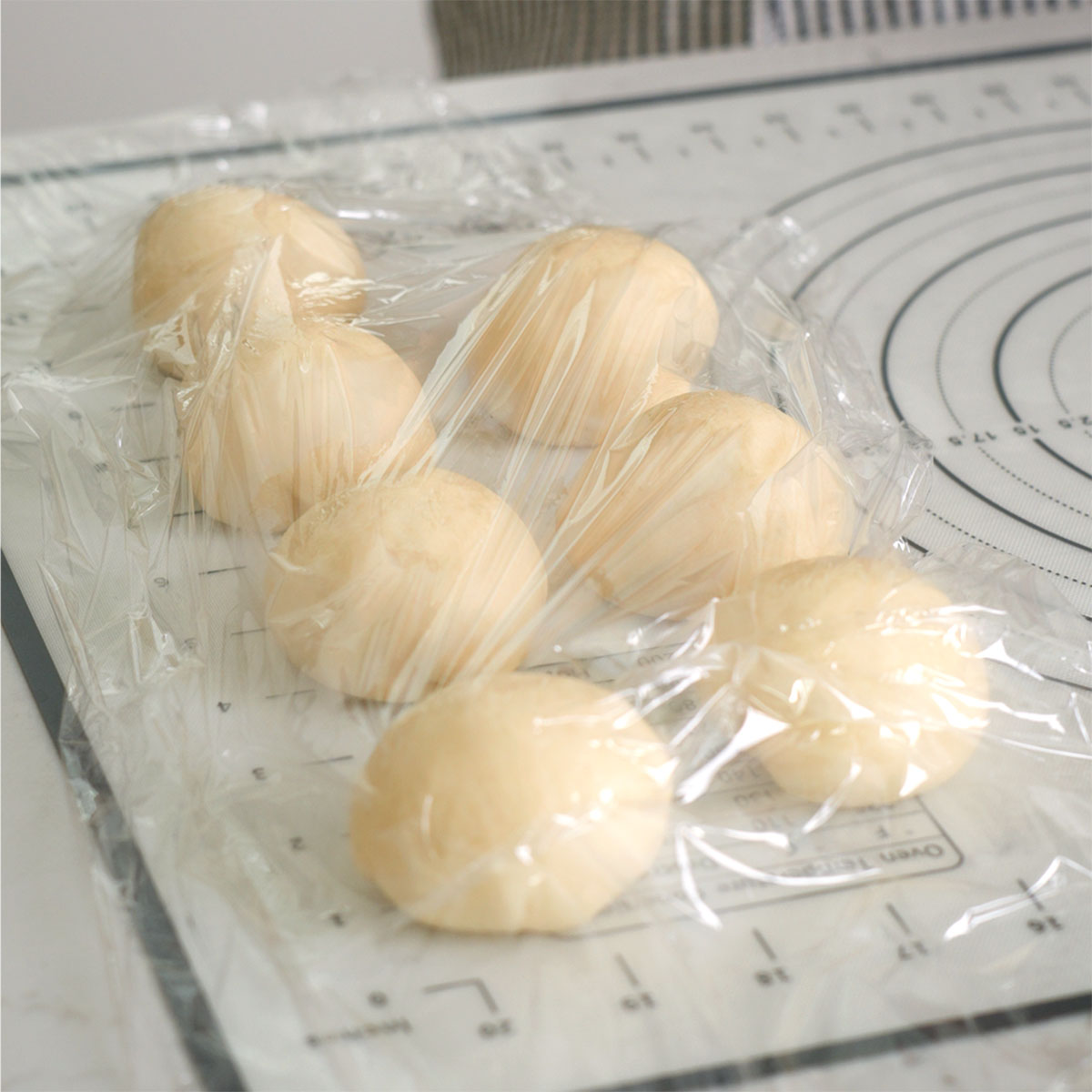 Balls of dough waiting until a layer of plastic wrap.