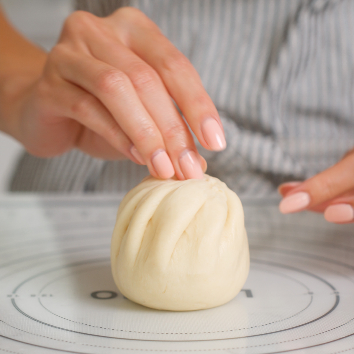 Pinching the dough on a banh bao to seal it.