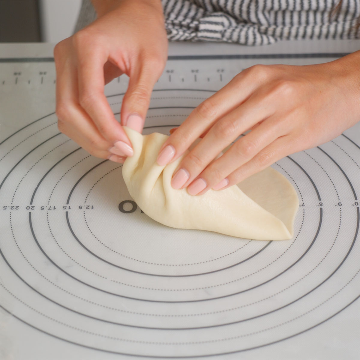 Pleating together dough around a meatball to form a banh bao.