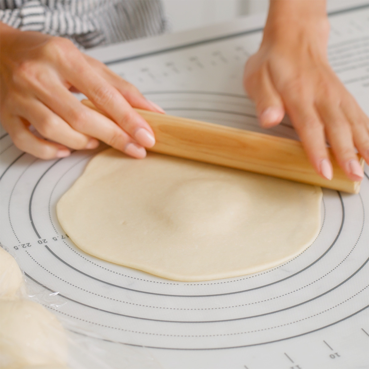 Rolling out a disc of dough with a thick center.