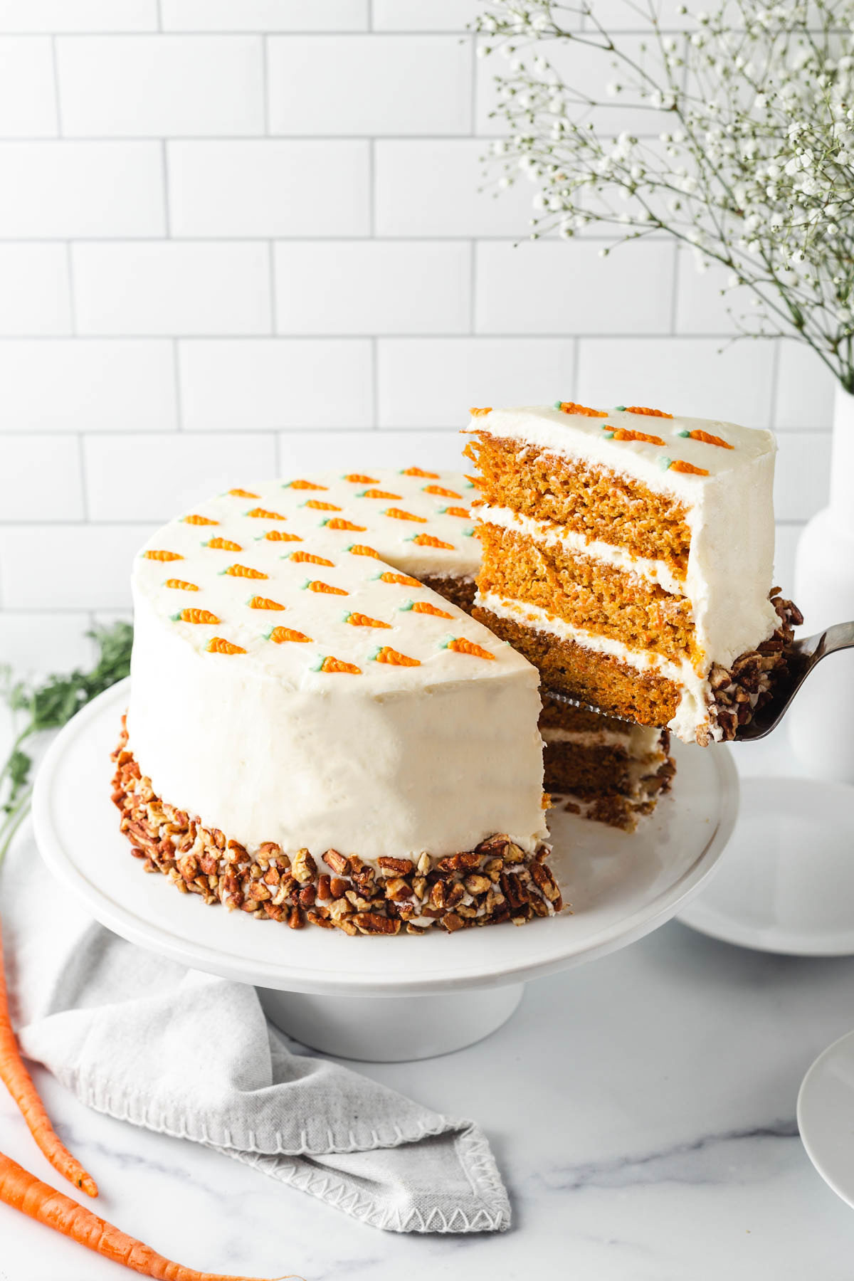 Cutting a slice of moist carrot cake with cream cheese frosting and pecans