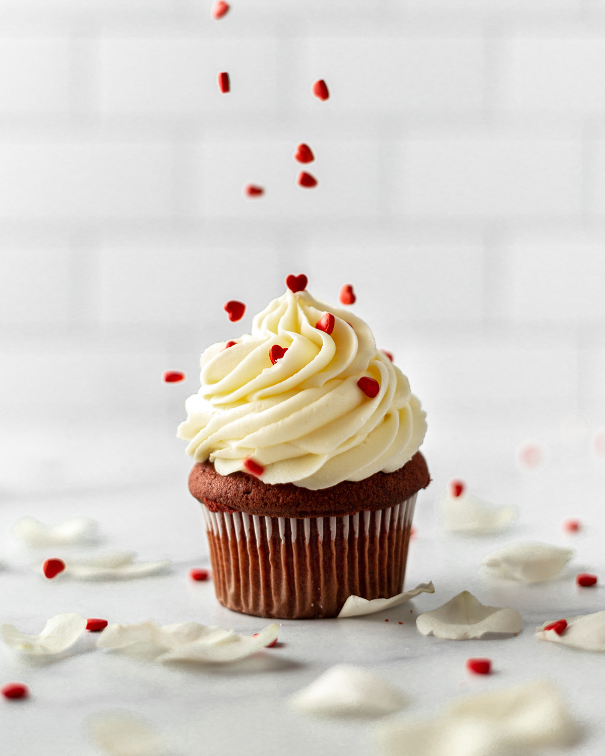 sprinkling sprinkles onto a cupcake