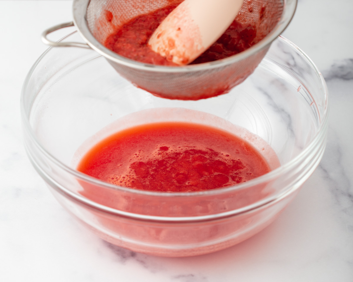 straining cooked strawberries into a bowl