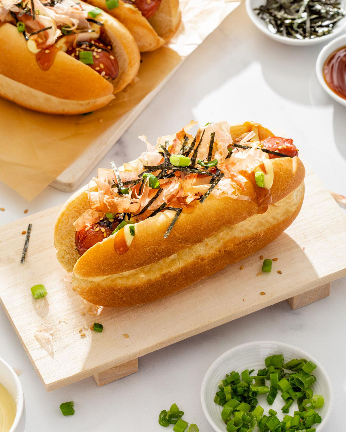 a japanese hot dog on a wood tray