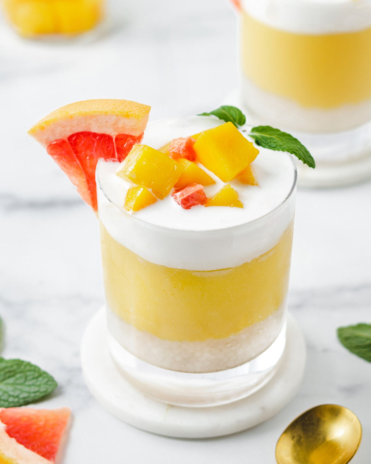 A glass with layered mango sage on a marble table up close