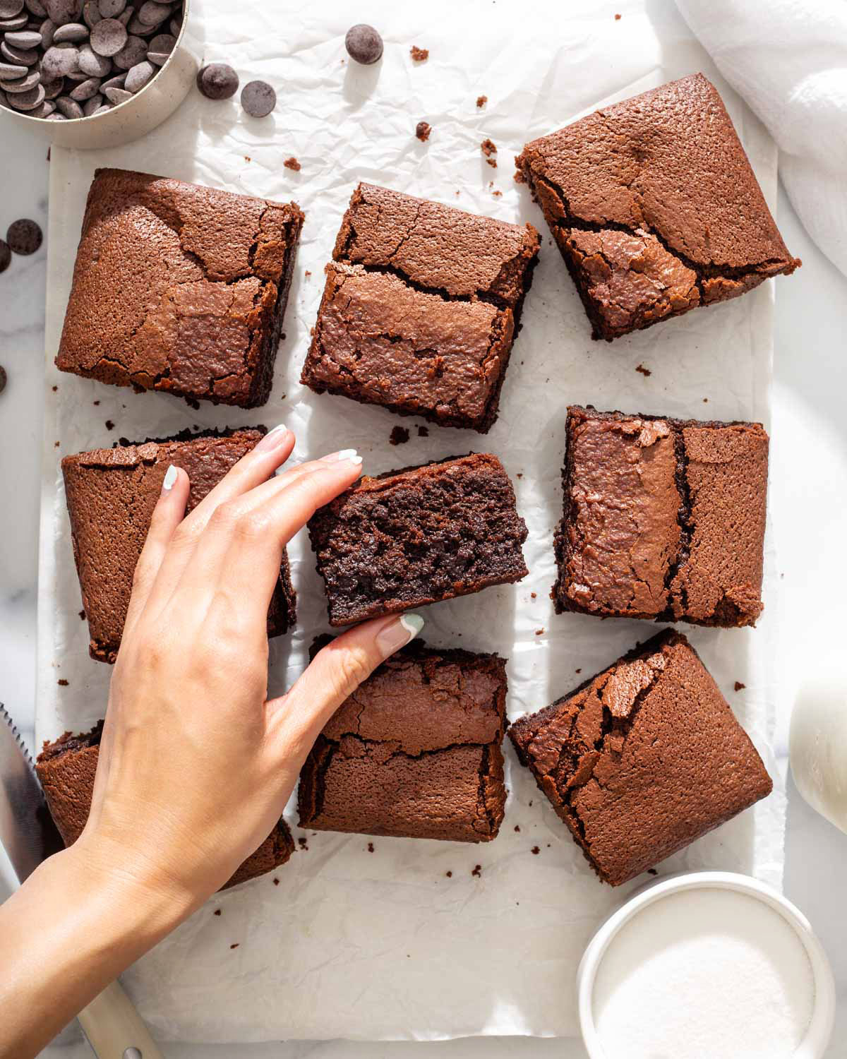 someone grabbing a mochi brownie from a platter of brownies