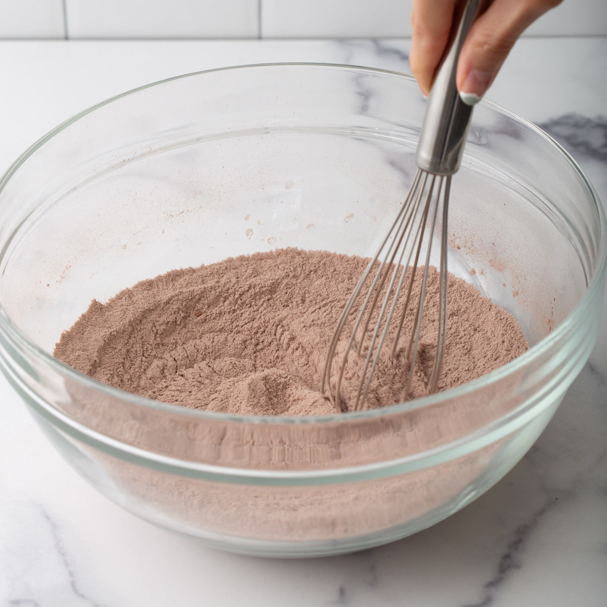 someone mixing brownie mix in a glass bowl