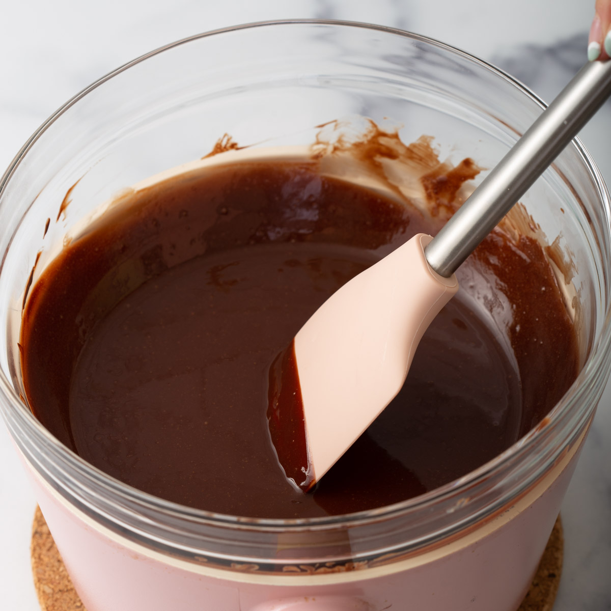 Someone mixing chocolate in a bowl over hot water