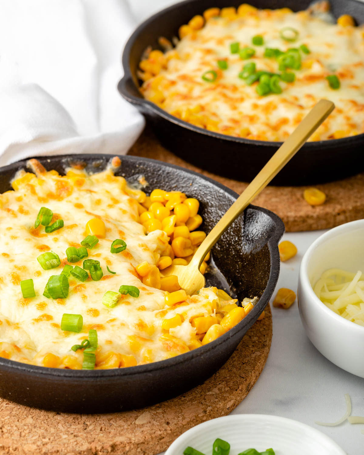 Two skillets of a Korean cheese corn on a table