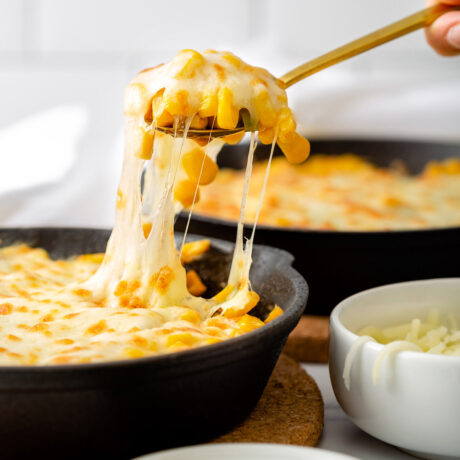 A close up of someone scooping up cheese corn