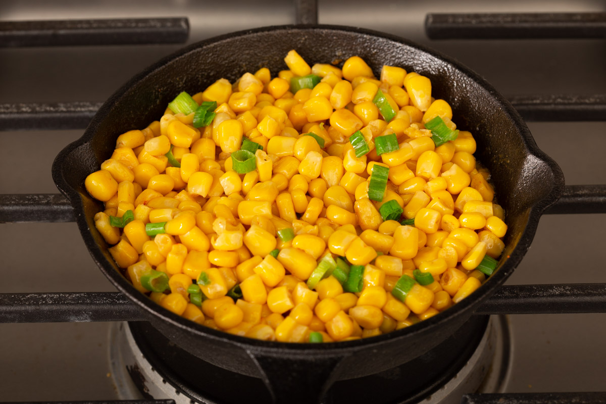 corn cooking in a small skillet on a stove