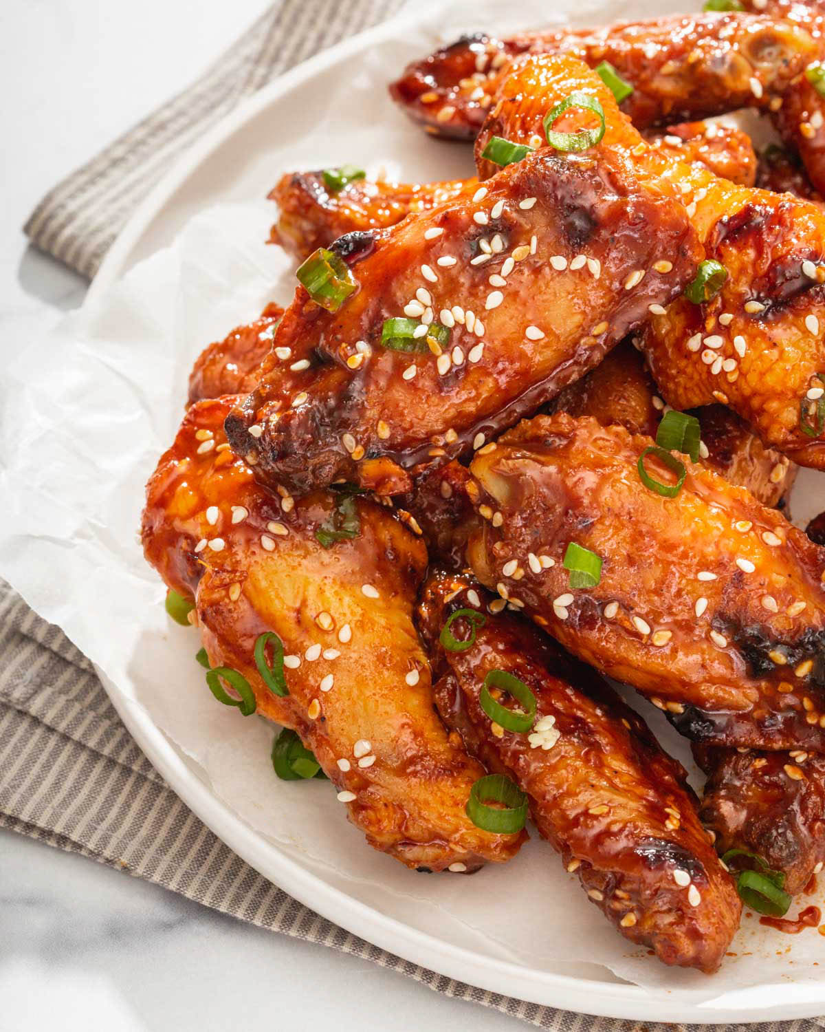 Close up of a plate of chicken wings with scallions and sesame seeds sprinkled on top.