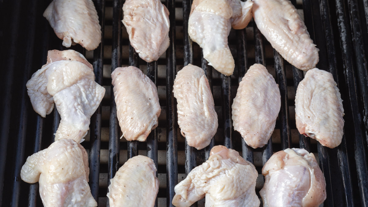 Overhead shot of raw chicken wings on a grill.