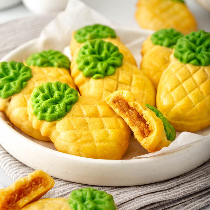 Close up of a plate of pineapple tarts with a bite out of one of them.