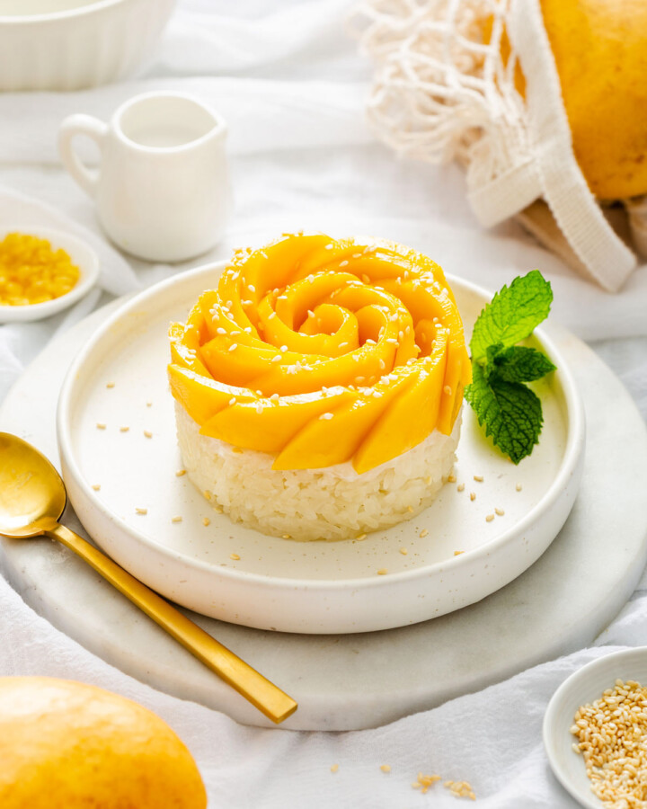 A plate of mango sticky rice presented with a mango rose