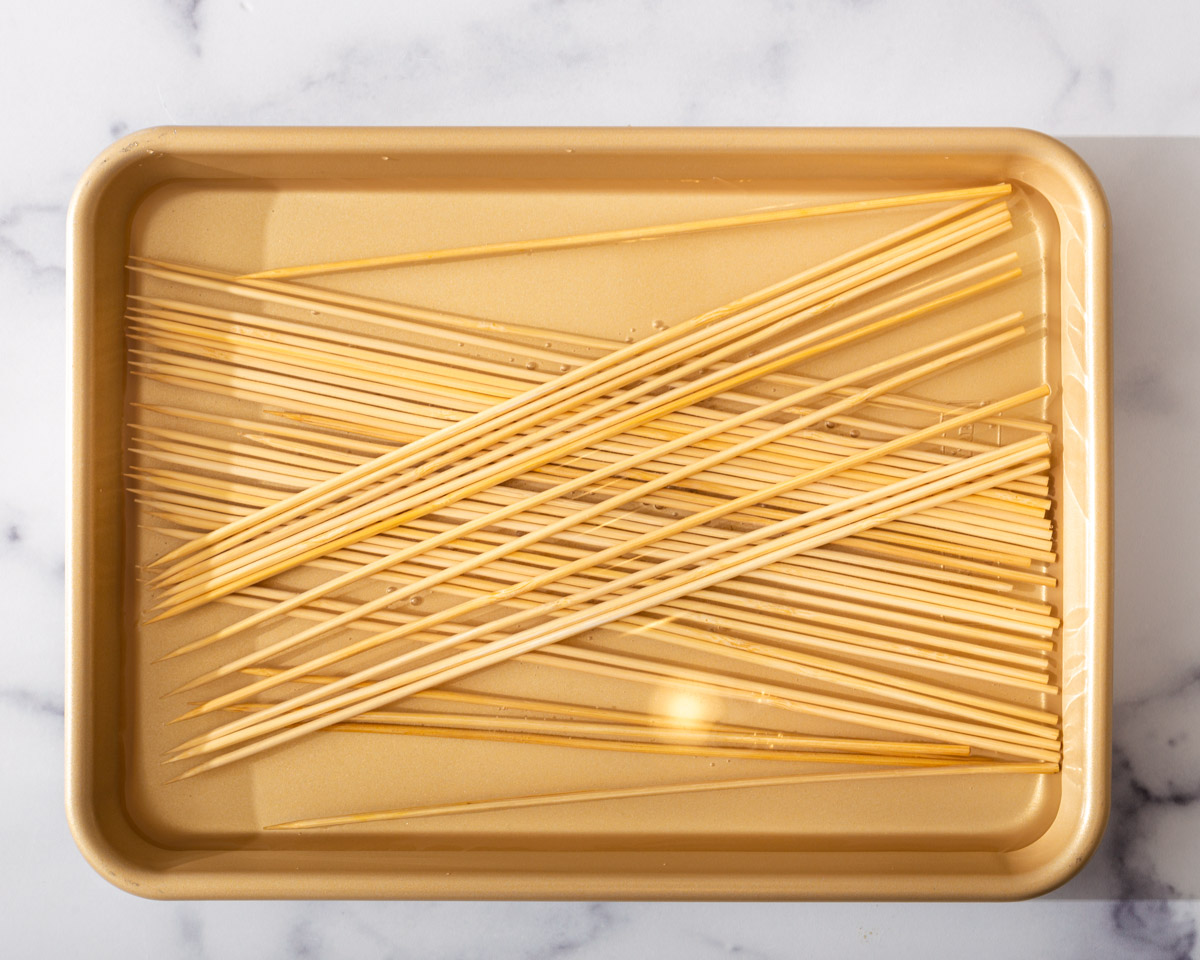 Bamboo skewers soaking in a tray of water.