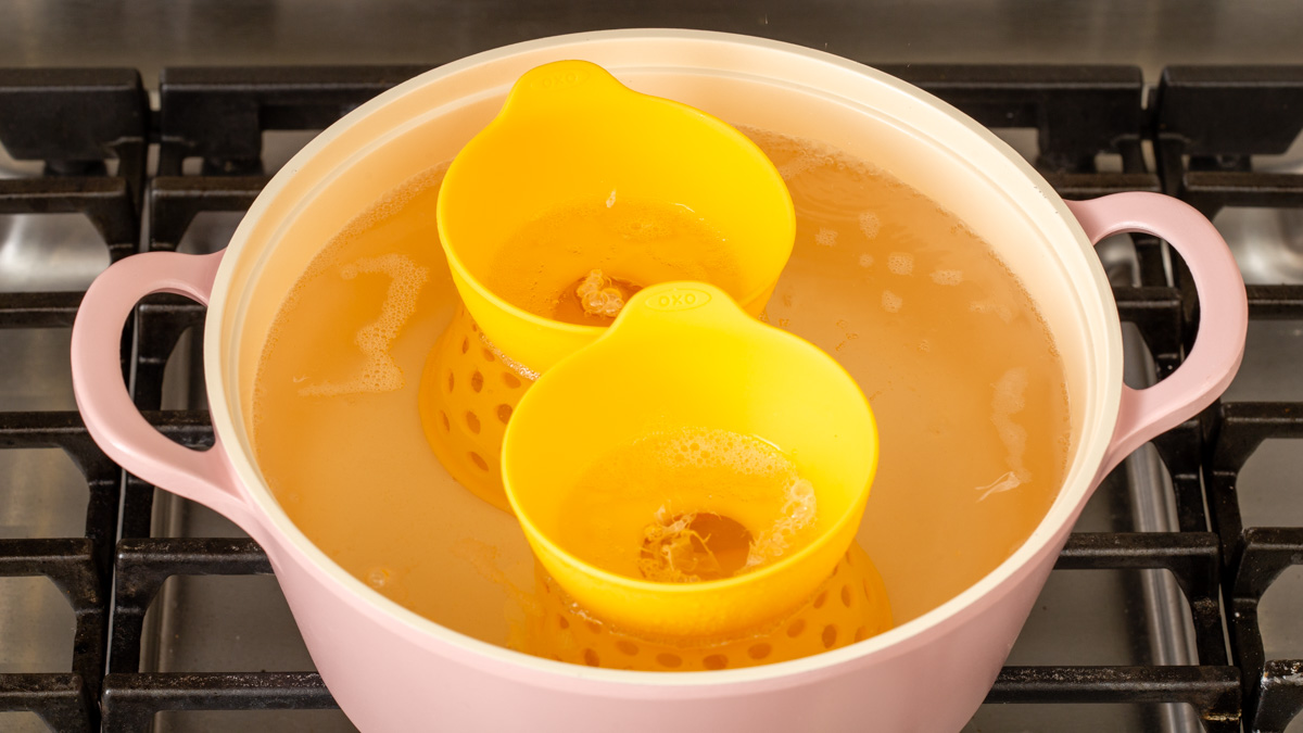 Poaching eggs in a pot of water with silicone egg poaching holders