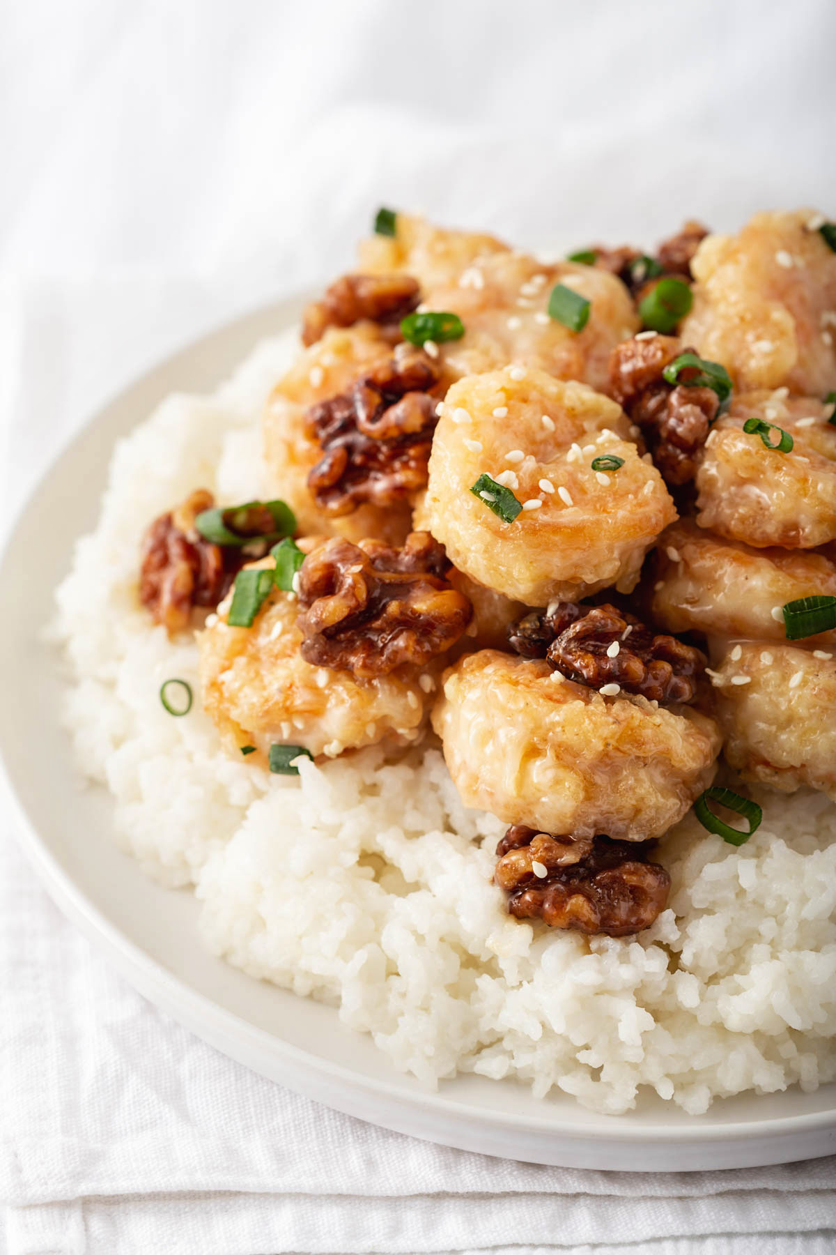 Up close of a plate of fried shrimp and walnuts on a bed of rice