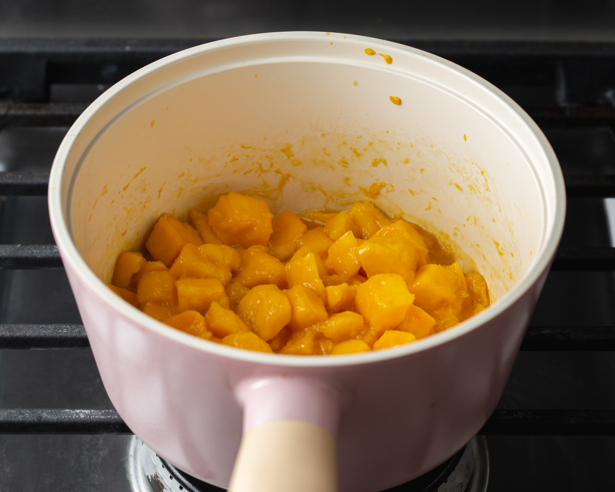 Cooking down freshly sliced chunks of mango on the stove