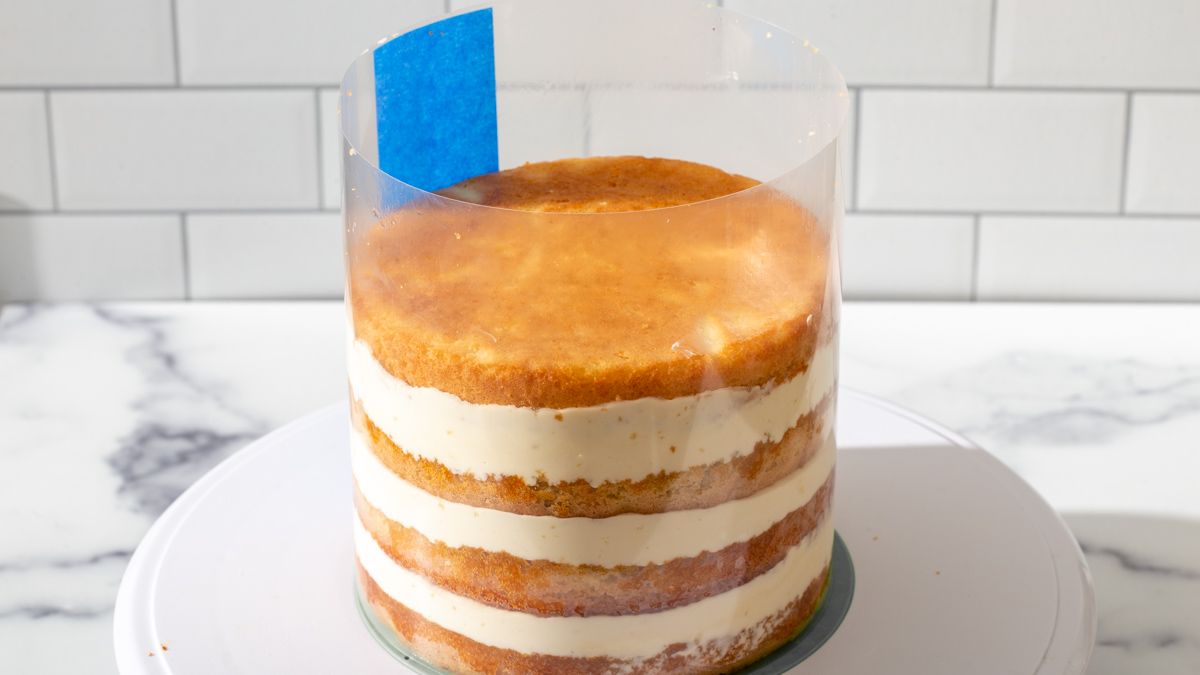 A round short cake layered with cream and wrapped in a cake collar