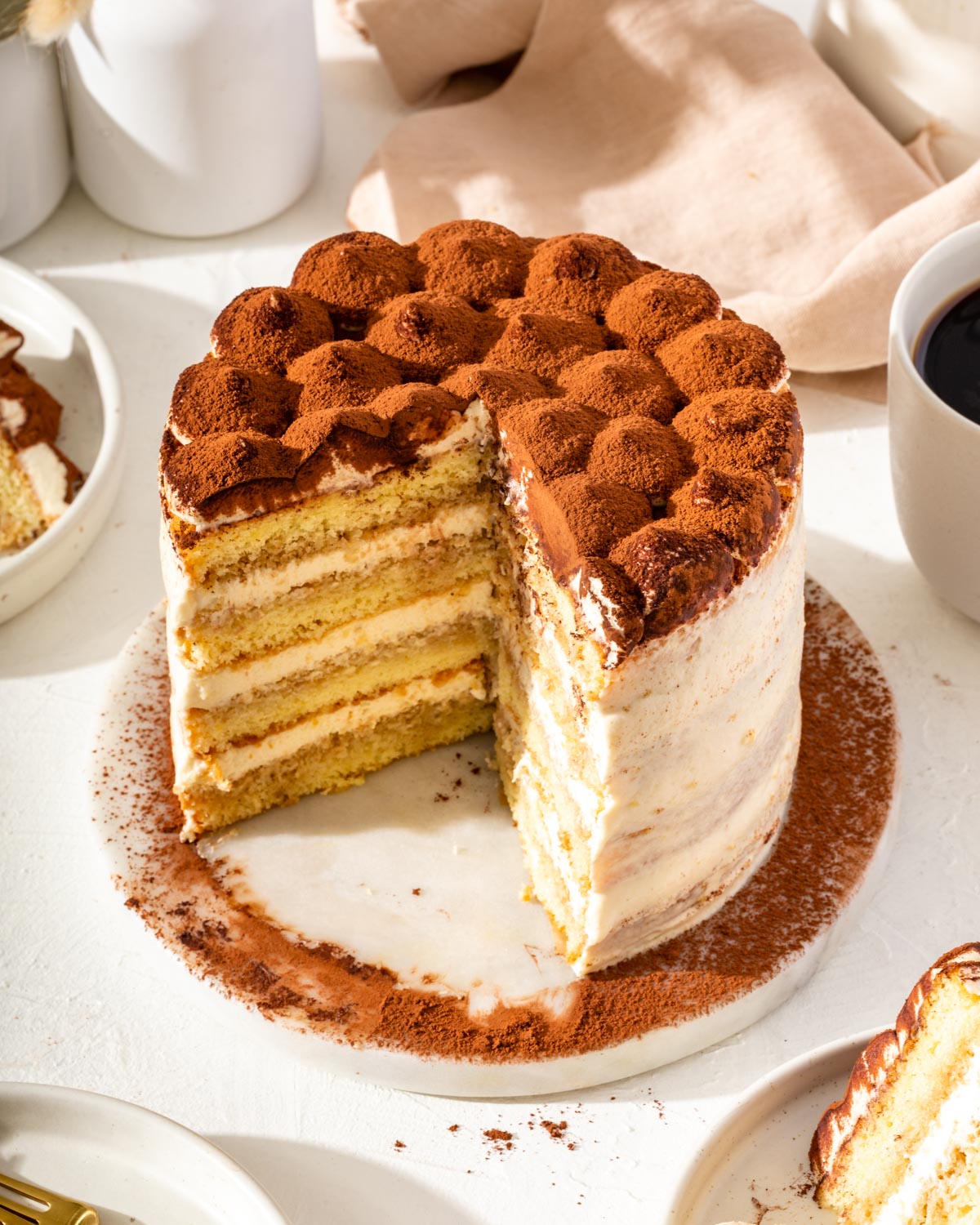 A tiramisu cake with a few slices out of it