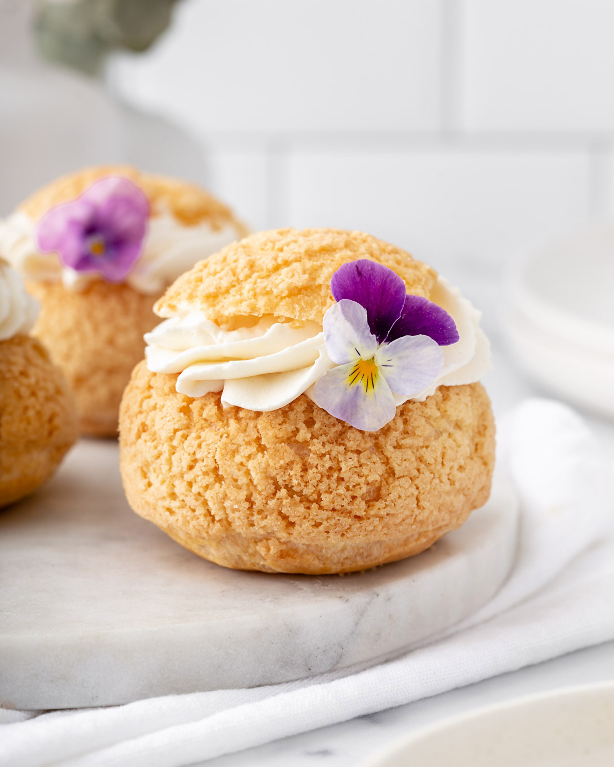 Close up of a creme puff garnished with a viola flower