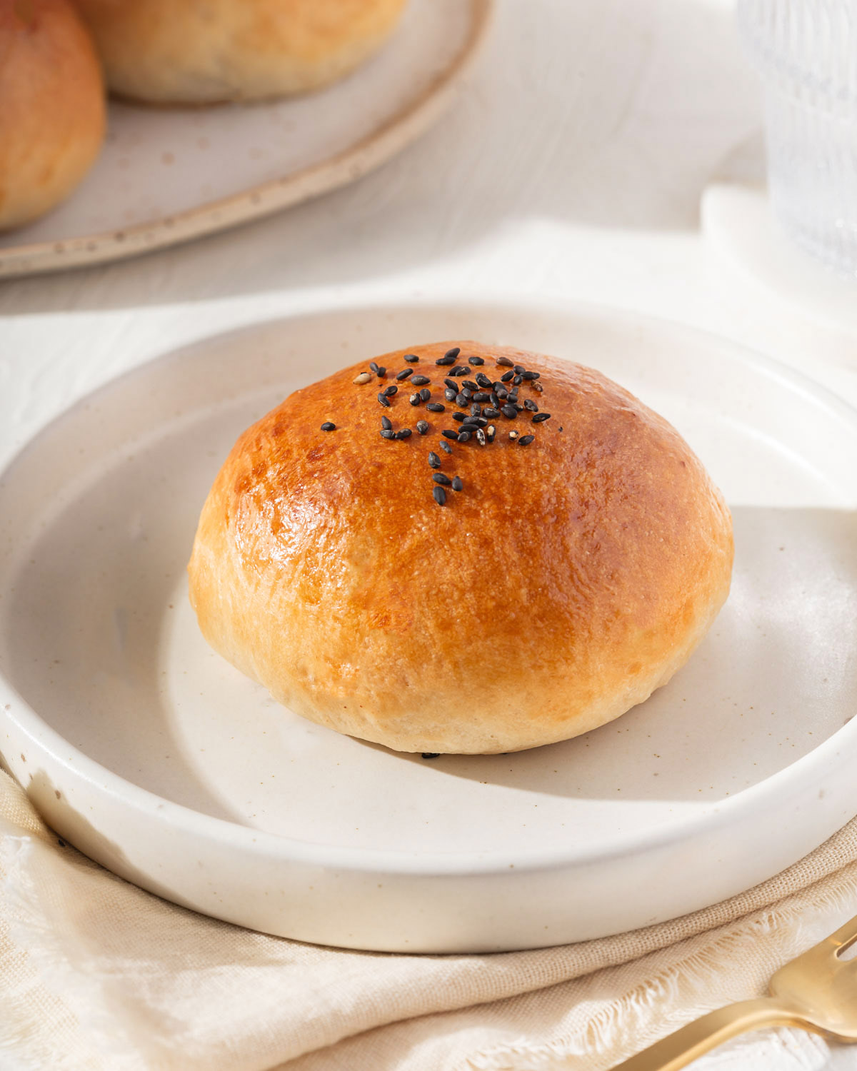 A baked Chinese BBQ pork bun on a plate.