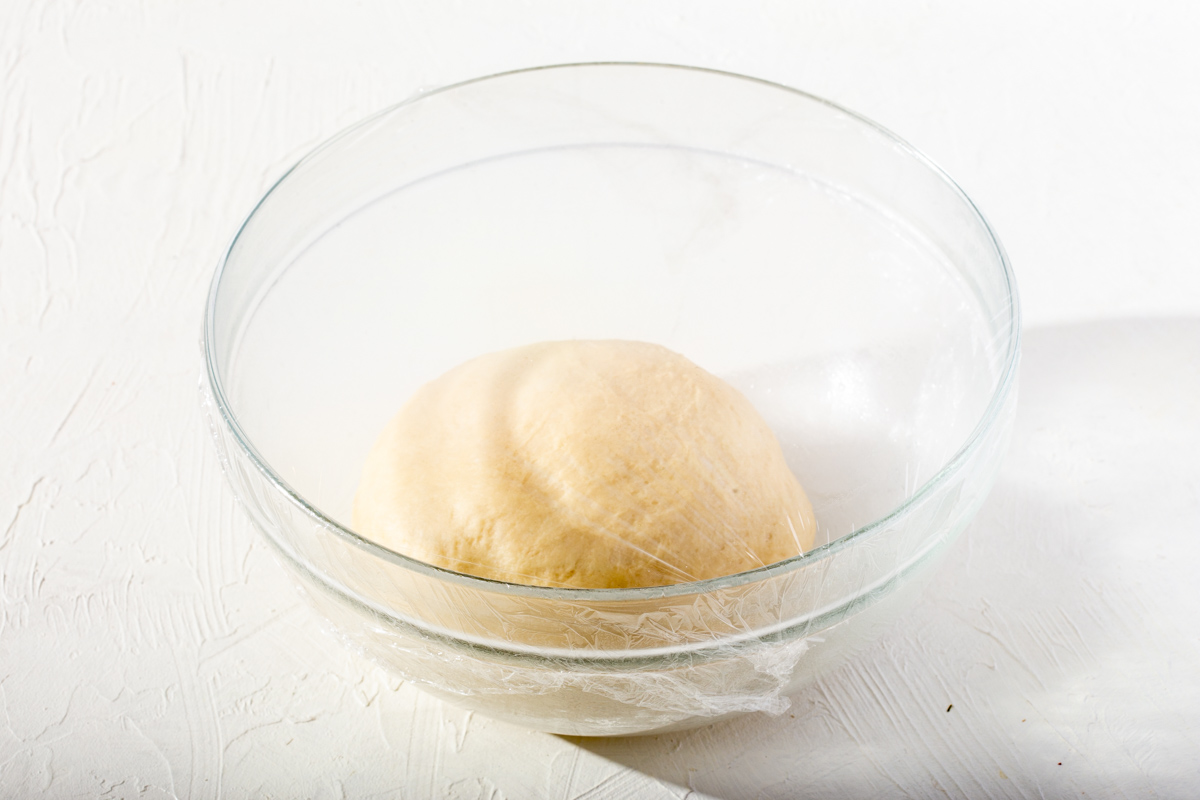 A ball of dough covered and ready to rise.