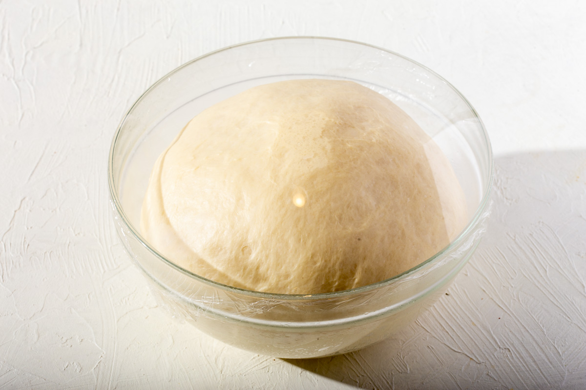 A risen ball of dough in a mixing bowl.