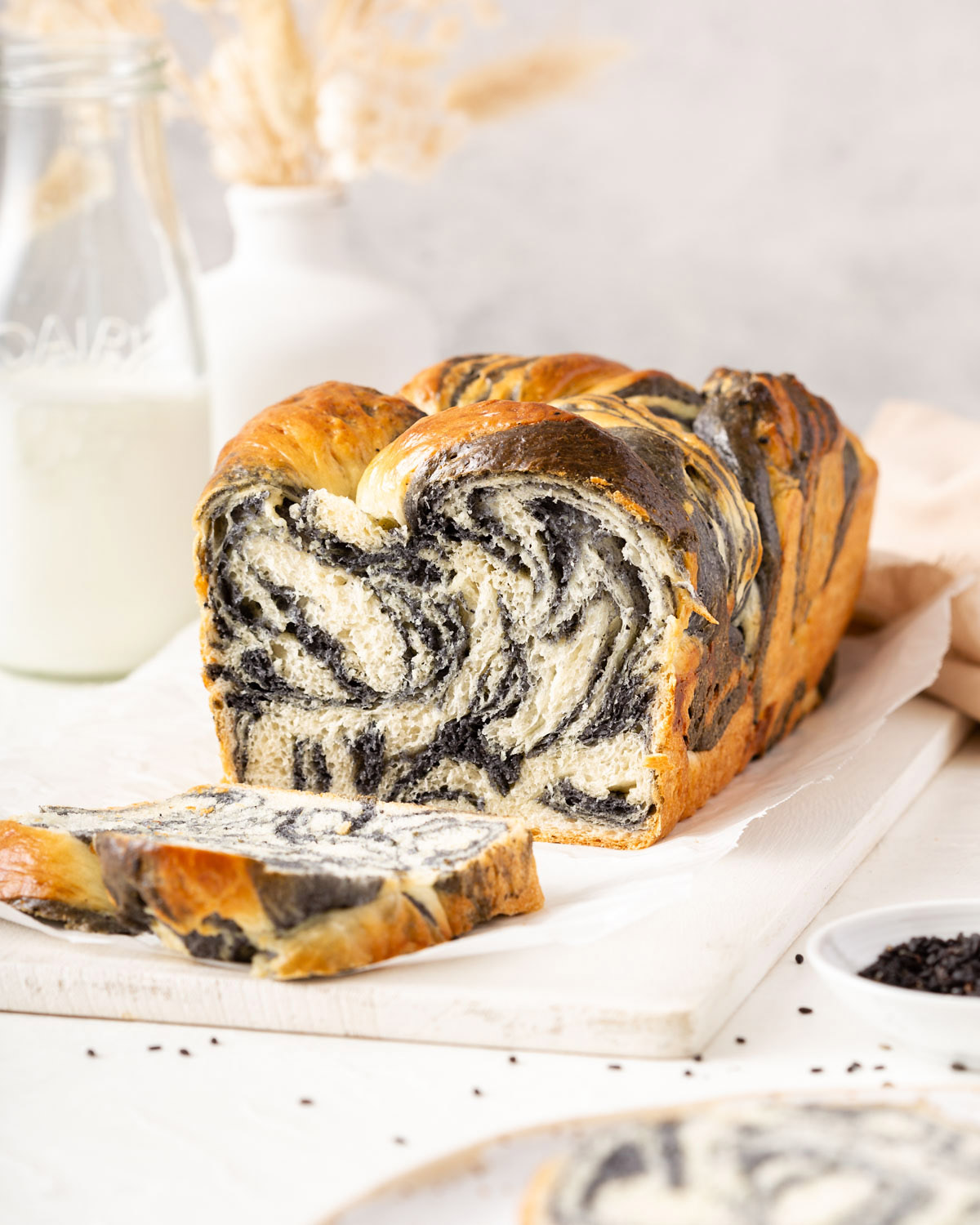 A loaf of marbled milk bread with a slice sitting in front of it.