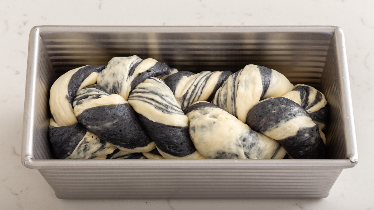 The braided dough inside a bread pan ready to rise.