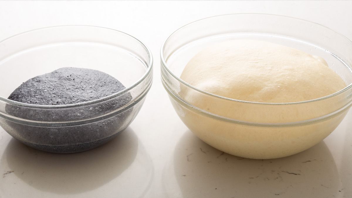 Two doughs in mixing bowls next to each other. One is black and the other is normal.