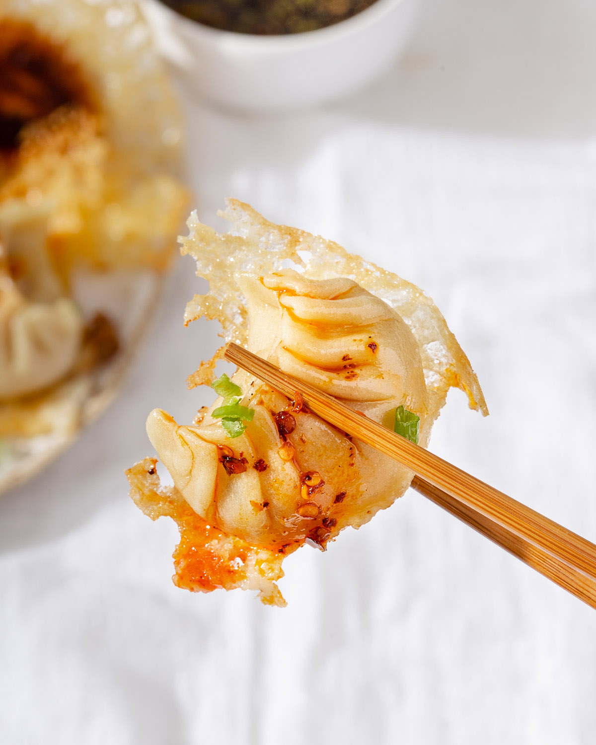 Holding up a crispy dumpling closely with a pair of chopsticks