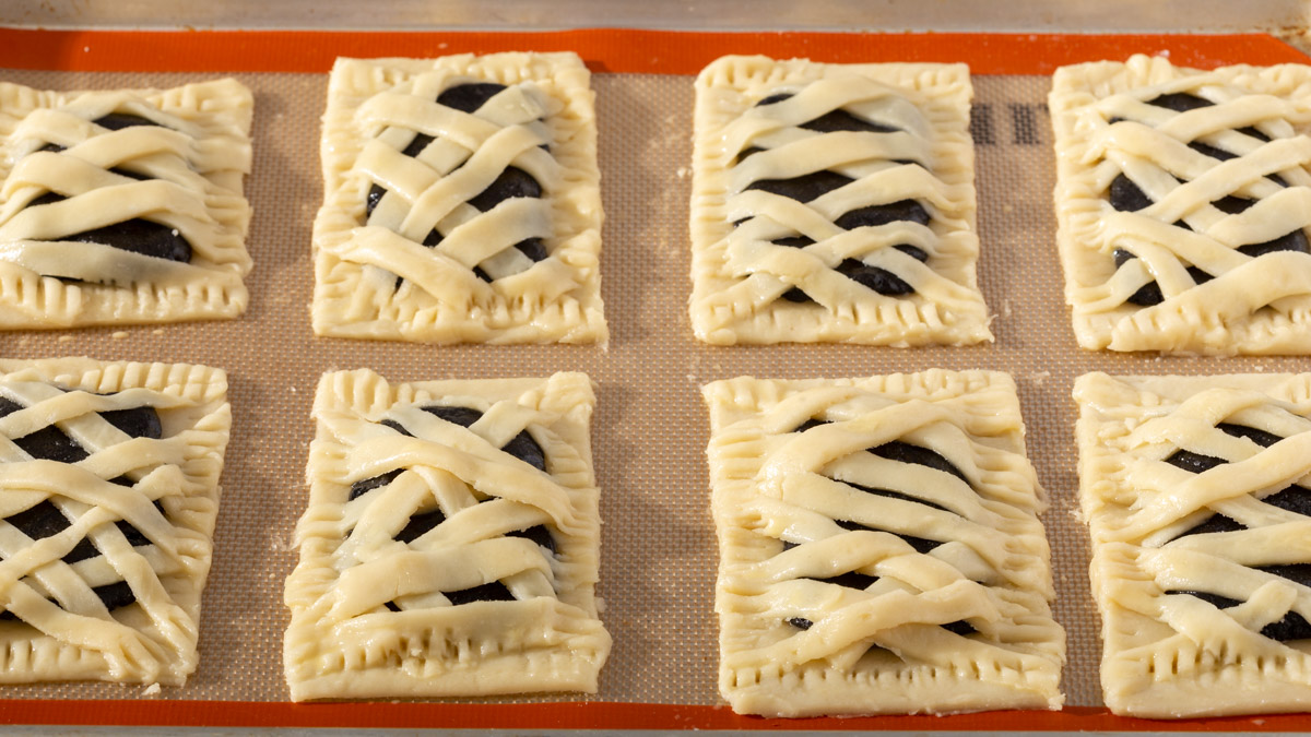 A tray of pop tarts after strip of dough were placed over the filling and base layer of dough