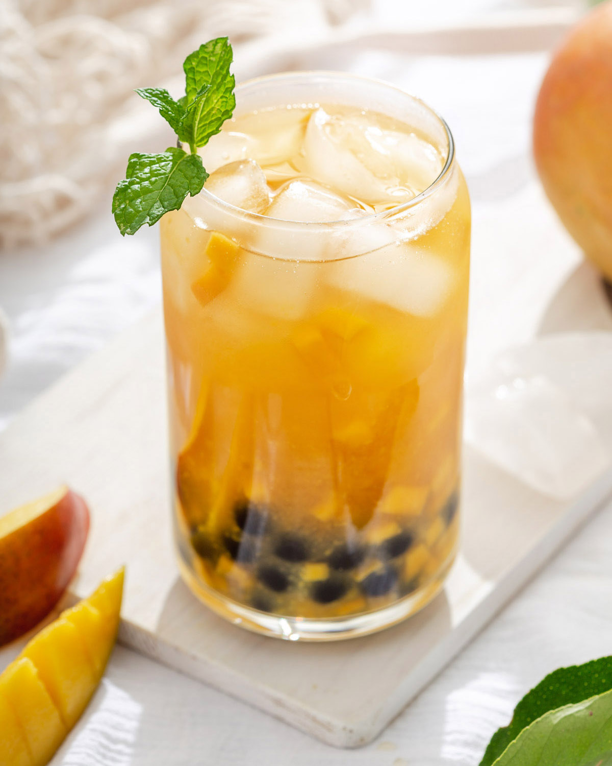 A glass of mango tea with boa on a serving platter with