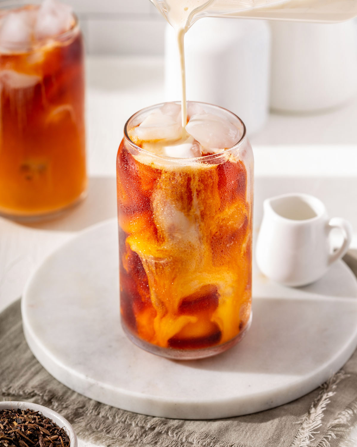 Pouring condensed milk cream into a glass Thai iced tea.