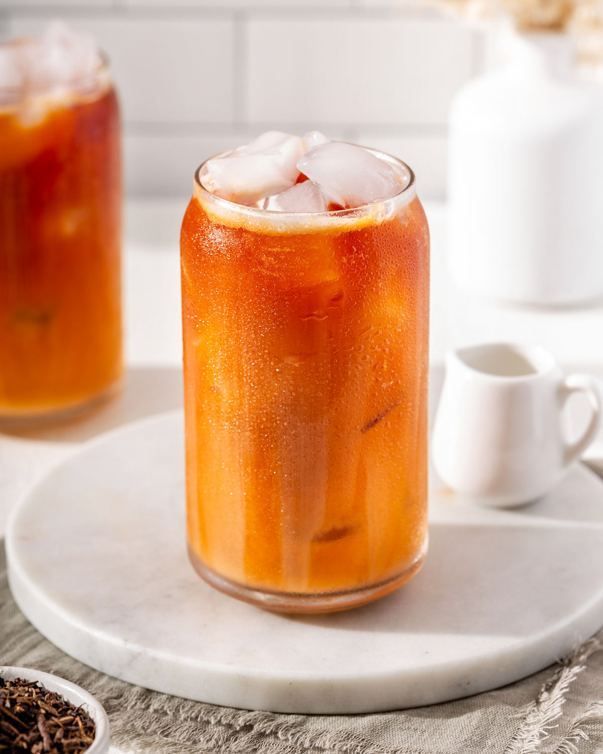 A glass of Thai iced tea on a round tray.