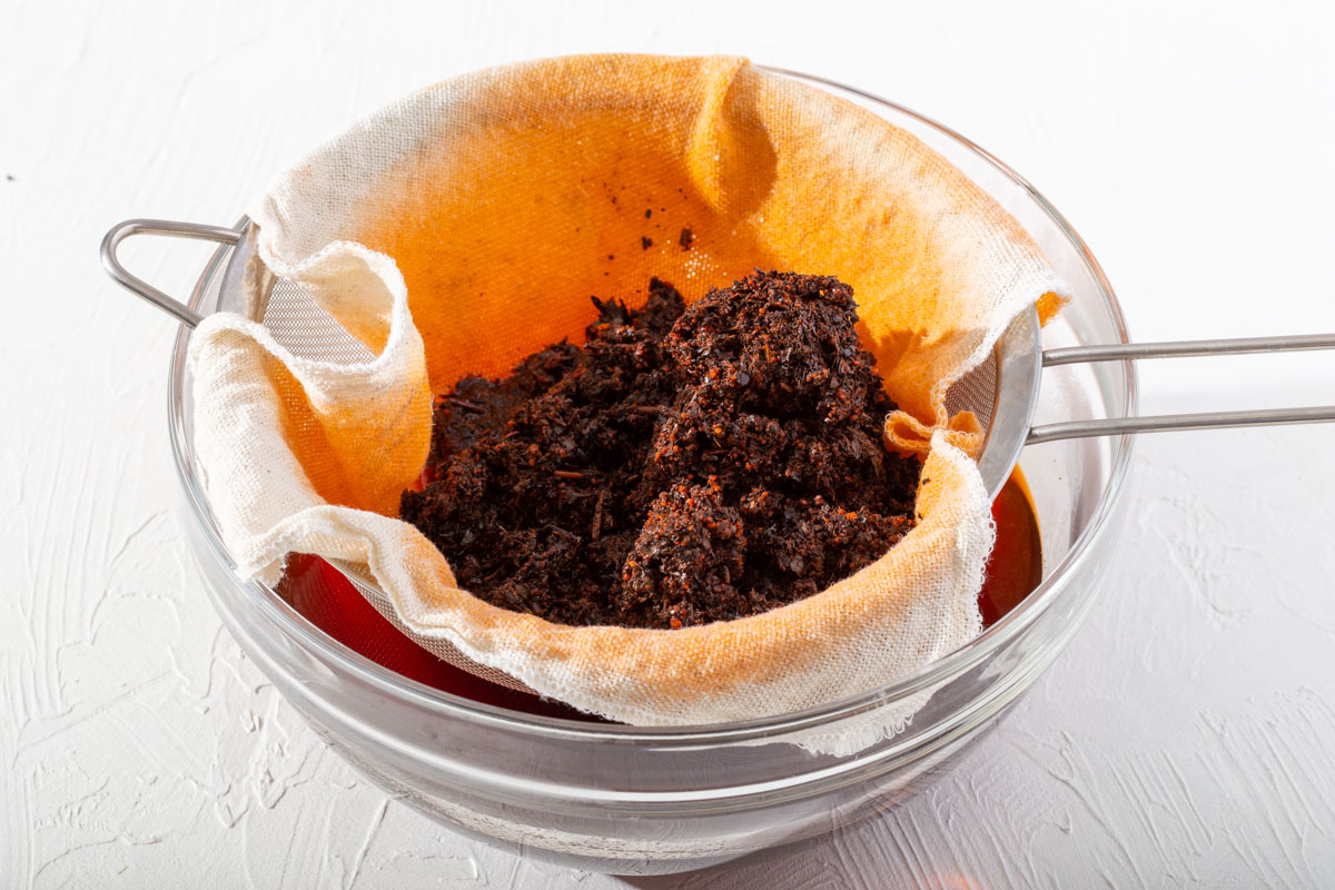 Thai tea draining through a cheese cloth and sifter.