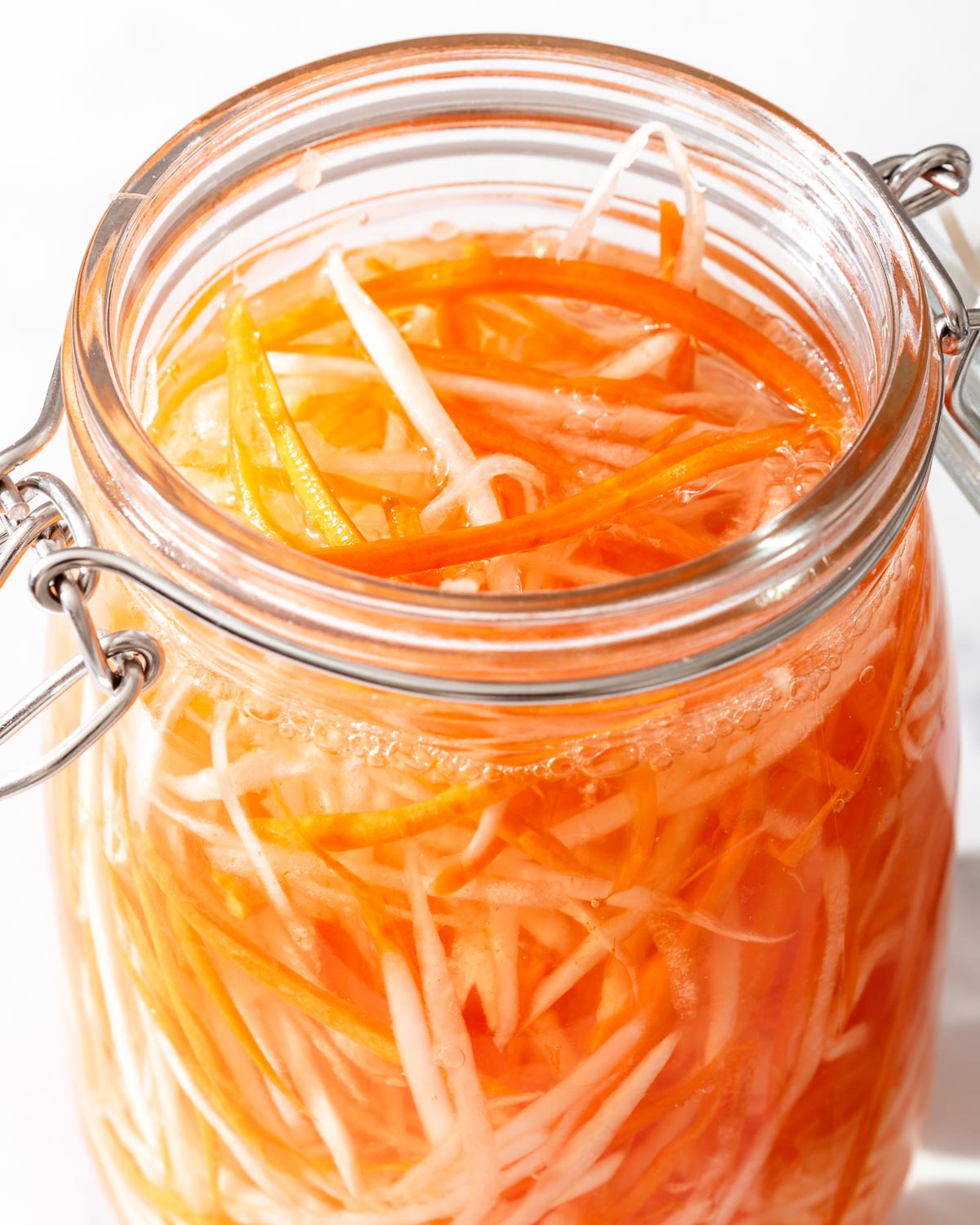 An open jar of pickling carrots and daikon