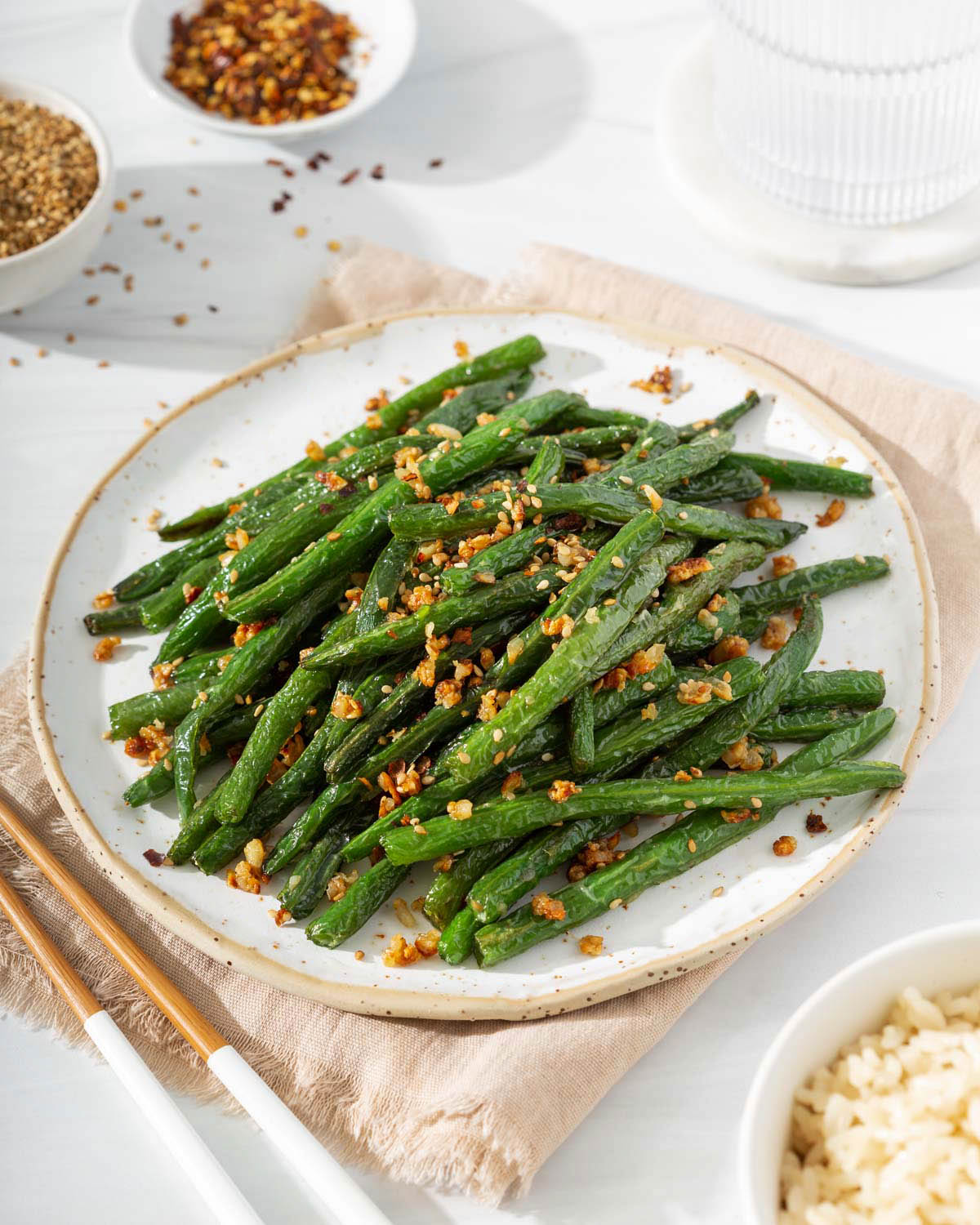 A plate of garlic green beans surrounded by a table spread