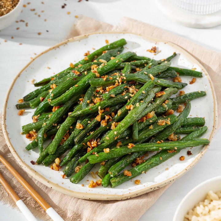 Up close of a plate of garlic green beans surrounded by a table spread