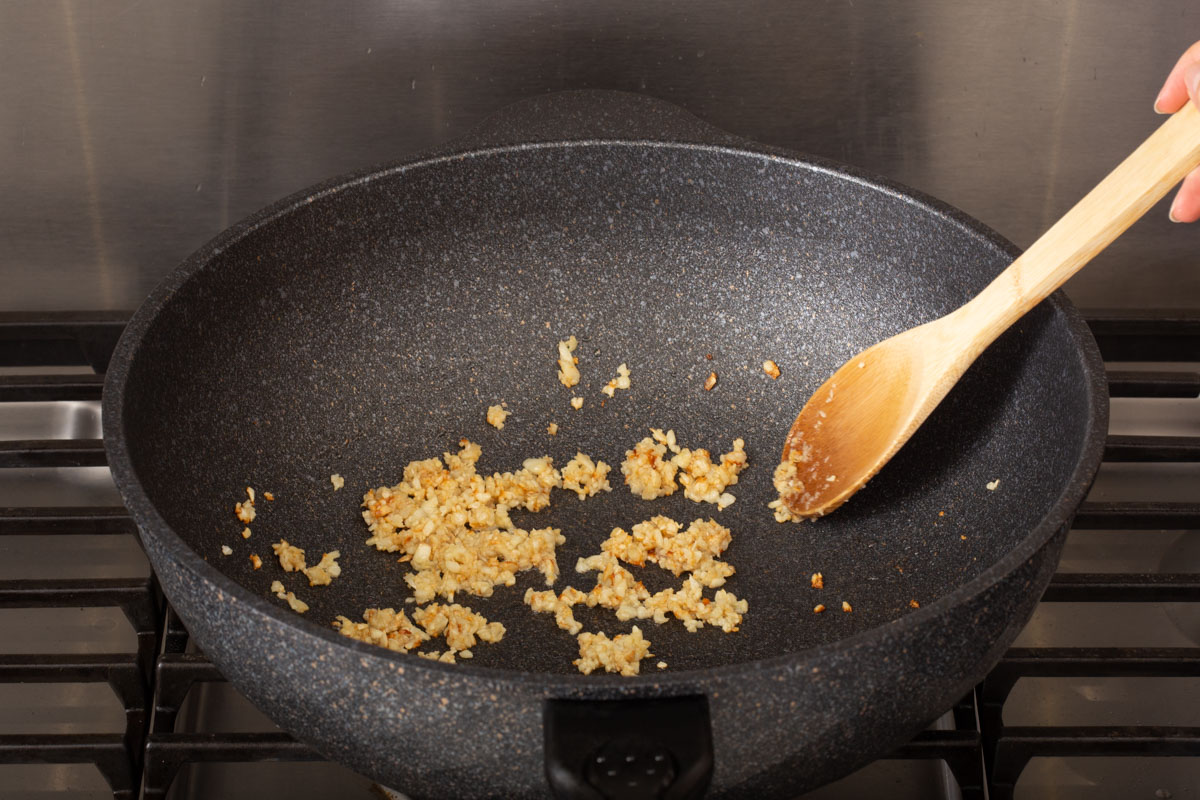 Sautéing minced garlic inside a wok