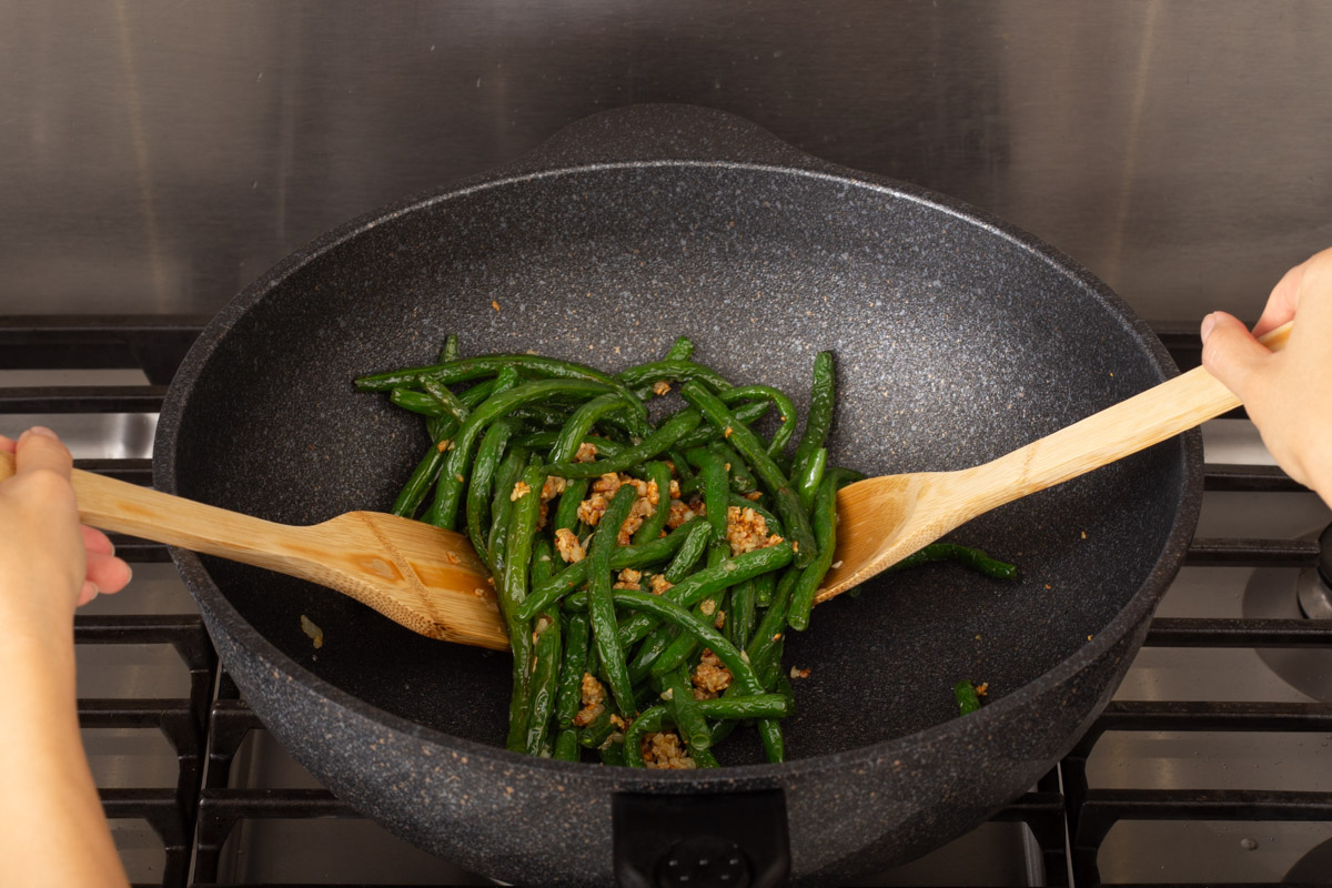 Tossing fried green beans with minced garlic