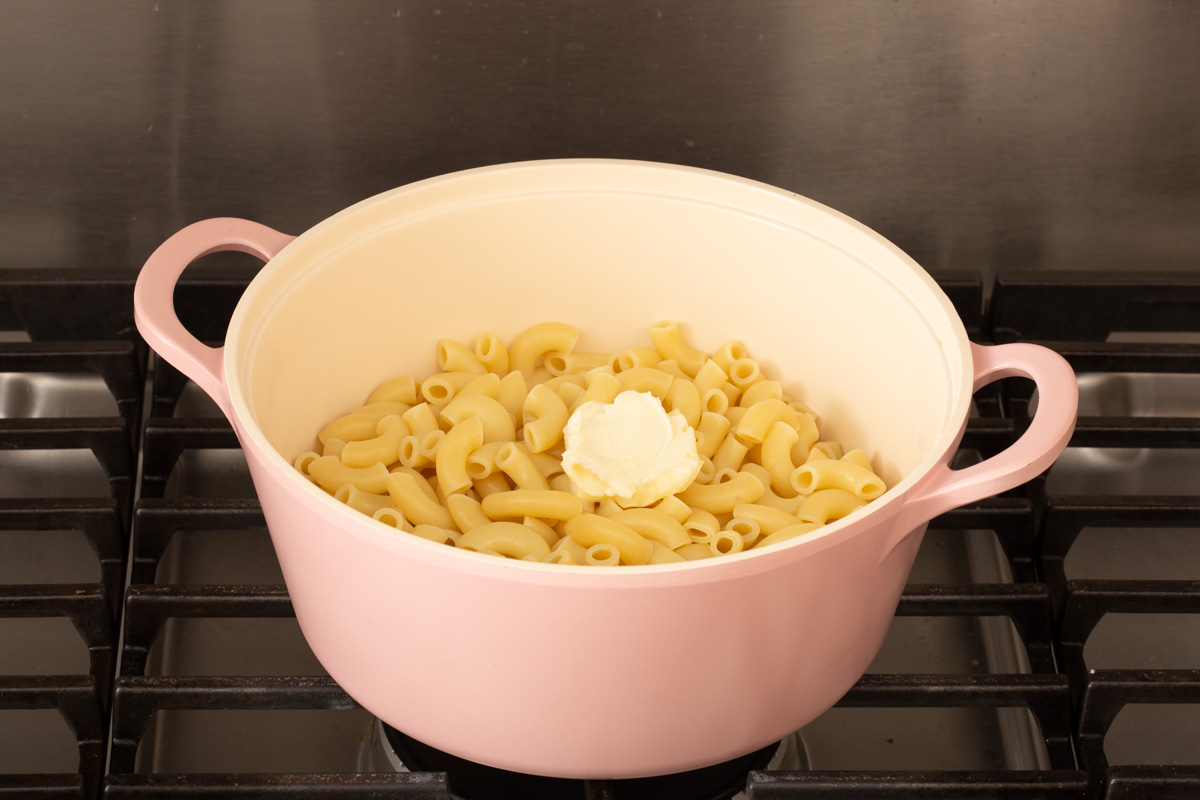 Melting butter into a pot of cooked elbow macaroni