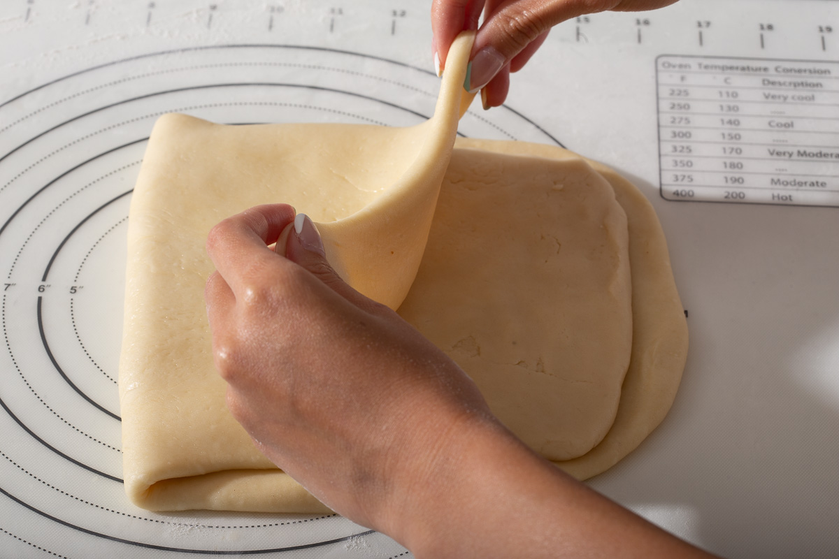 Folding the bottom dough over the second dough to sandwich it like a hotdog