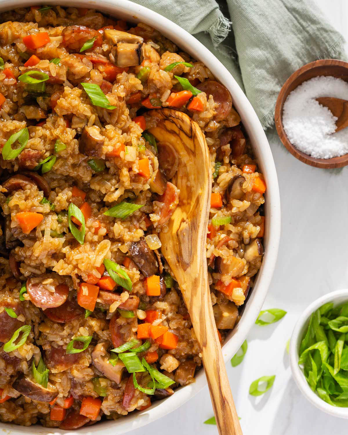 Up close of a serving platter of stuffing with a wooden spoon scooping out a serving.